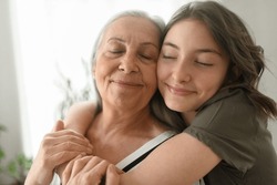Senior grandmother with teenage granddaguhter hugging together at home., a Person Photo by Halfpoint