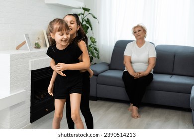 senior grandmother workout yoga withgranddaughters preschooler. They are sitting on mat at cozy home interior. Sport, parenthood and people concept - Powered by Shutterstock