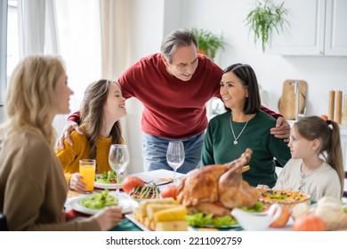 Senior Grandparent Hugging Multiethnic Family Near Thanksgiving Dinner At Home