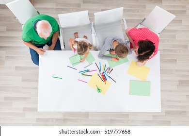 Senior Grandparents Drawing With Kids Doing Arts And Crafts Together At Home