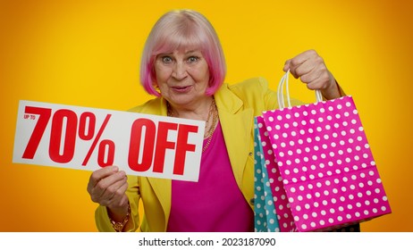 Senior granny woman showing shopping bags and Up To 70 Percent Off inscriptions banner text. Black Friday. Good holiday discounts, low prices for shopping. Elderly old grandmother on orange background - Powered by Shutterstock