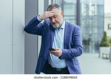 Senior Gray-haired Businessman In Despair Upset Reading Bad News On Phone, Man Outside Office Building In Business Suit, Bankrupt Investor Lost Money, Banker In Depression