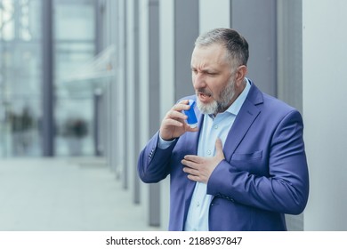 Senior Gray-haired Businessman Sick Has Asthma Attack Difficult To Breathe, Man Outside Office Building In Business Clothes Uses Inhaler To Ease Breathing