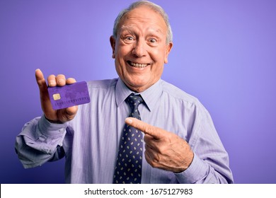 Senior Grey Haired Business Man Holding Credit Card Over Purple Background Very Happy Pointing With Hand And Finger