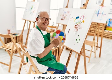 Senior grey-haired artist man smiling happy painting at art studio. - Powered by Shutterstock