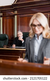 Senior Grey-haired Judge Looking At Advocate On Blurred Foreground