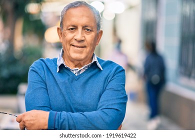 Senior grey-haired man with arms crossed smiling happy standing at the city.