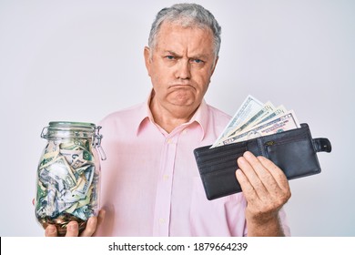 Senior Grey-haired Man Holding Wallet With Dollars And Jar With Savings Skeptic And Nervous, Frowning Upset Because Of Problem. Negative Person. 