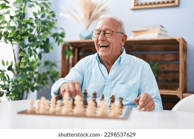 Senior grey-haired man smiling confident playing chess at home - Powered by Shutterstock