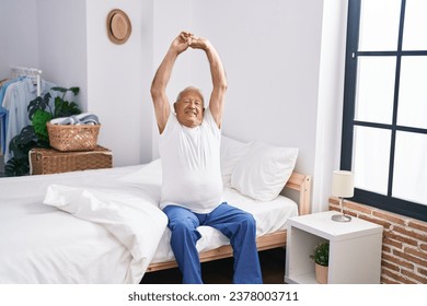 Senior grey-haired man waking up stretching arms at bedroom - Powered by Shutterstock