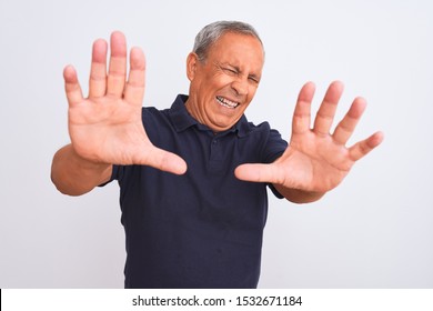 Senior Grey-haired Man Wearing Black Casual Polo Standing Over Isolated White Background Afraid And Terrified With Fear Expression Stop Gesture With Hands, Shouting In Shock. Panic Concept.