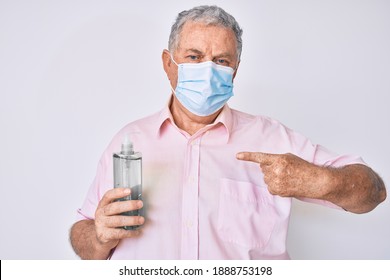 Senior grey-haired man wearing medical mask holding hand sanitizer gel pointing finger to one self smiling happy and proud  - Powered by Shutterstock