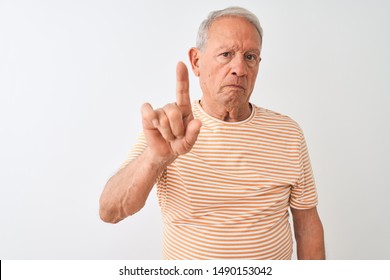 Senior grey-haired man wearing striped t-shirt standing over isolated white background Pointing with finger up and angry expression, showing no gesture