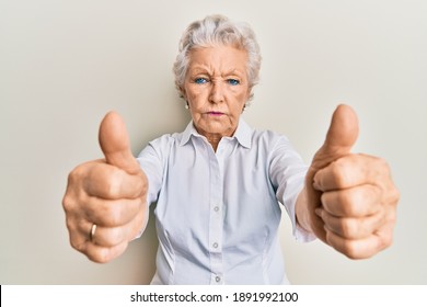 Senior grey-haired woman doing thumbs up positive gesture depressed and worry for distress, crying angry and afraid. sad expression. 