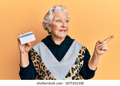 Senior Grey-haired Woman Holding Credit Card Smiling Happy Pointing With Hand And Finger To The Side 