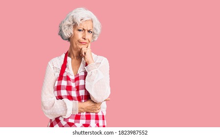 Senior grey-haired woman wearing apron serious face thinking about question with hand on chin, thoughtful about confusing idea  - Shutterstock ID 1823987552