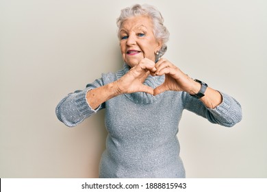 Senior grey-haired woman wearing casual clothes smiling in love doing heart symbol shape with hands. romantic concept. 