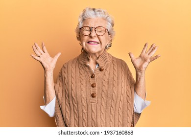 Senior grey-haired woman wearing casual clothes and glasses celebrating mad and crazy for success with arms raised and closed eyes screaming excited. winner concept  - Powered by Shutterstock