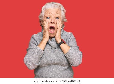 Senior Grey-haired Woman Wearing Casual Winter Sweater Afraid And Shocked, Surprise And Amazed Expression With Hands On Face 