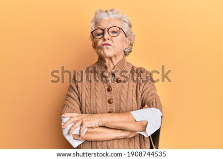 Senior grey-haired woman wearing casual clothes and glasses skeptic and nervous, disapproving expression on face with crossed arms. negative person. 