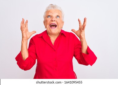 Senior Grey-haired Woman Wearing Red Casual Shirt Standing Over Isolated White Background Crazy And Mad Shouting And Yelling With Aggressive Expression And Arms Raised. Frustration Concept.