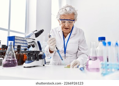 Senior grey-haired woman wearing scientist uniform using pipette at laboratory - Powered by Shutterstock