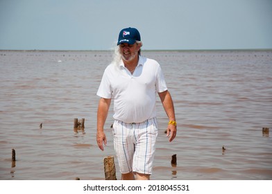 Senior Grizzled Man With Long Gray Hair. Sos Cuba. Adult Male Cuban. Old Cuban Man In Cap With Flag.