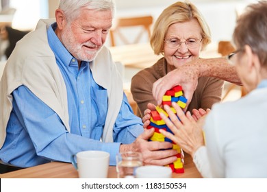 Senior Group With Dementia Stacks Together Colorful Building Blocks In Retirement Home