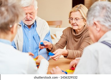 Senior Group Plays With Colorful Building Blocks In A Dementia Therapy At Retirement Home