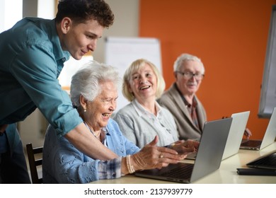 Senior Group In Retirement Home With Young Instructor Learning Together In Computer Class