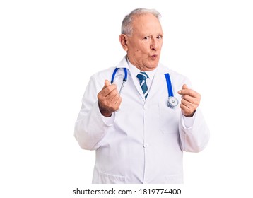 Senior Handsome Grey-haired Man Wearing Doctor Coat And Stethoscope Doing Money Gesture With Hands, Asking For Salary Payment, Millionaire Business 