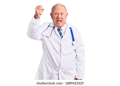 Senior handsome grey-haired man wearing doctor coat and stethoscope angry and mad raising fist frustrated and furious while shouting with anger. rage and aggressive concept. 