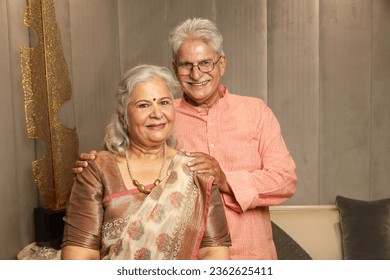 Senior handsome indian asian man presenting his wife looking in front of the camera on diwali or anniversary. happy diwali theme concepts wearing indian traditional ethnic kurta pajama and saree. - Powered by Shutterstock