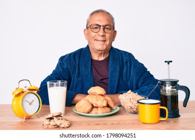 Senior Handsome Man With Gray Hair Sitting On The Table Eating Breakfast In The Morning With A Happy And Cool Smile On Face. Lucky Person. 