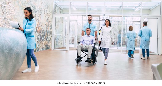 Senior handsome man in a wheelchair is moving in the hospital with help of medical special staff  - Powered by Shutterstock