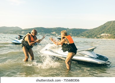 Senior happy couple having playful fun at jet ski on beach island hopping tour - Active elderly travel concept around the world with retired people riding water scooter jetski - Bright vintage filter - Powered by Shutterstock