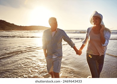 Senior, happy couple and holding hands with beach sunset for support, love or bonding in nature. Man, woman or lovers walking with smile on outdoor summer holiday by water or ocean coast in sunshine - Powered by Shutterstock