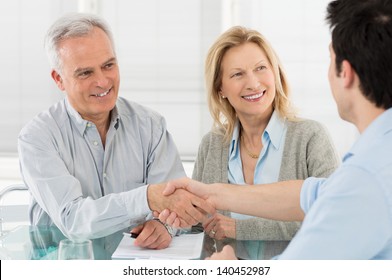 Senior Happy Couple Shaking Hand With Financial Advisor