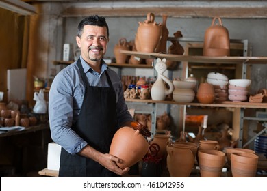 Senior happy craftsman with ceramic crockery in hands in studio - Powered by Shutterstock