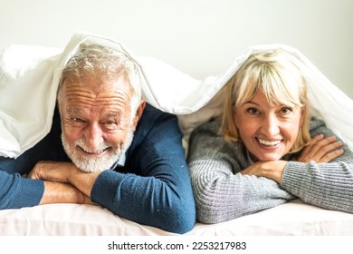 Senior happy love elder couple relaxing and talking together and look at camara lying on bed in bedroom at home.Retirement healthcare couple concept - Powered by Shutterstock