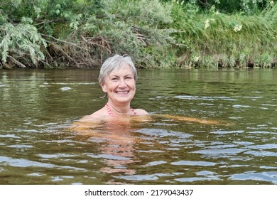 Senior Happy Smiling Woman Swimming In A Calm River In The Countryside, Looking At A Camera. Physical Health Concept