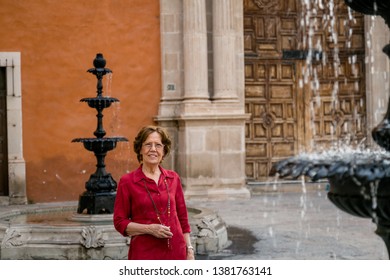 Senior Happy Woman Walking Around A Big Antique House. Mexico