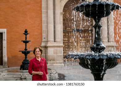 Senior Happy Woman Walking Around A Big Antique House. Mexico