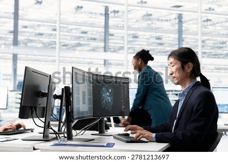 Senior hardware developer in semiconductor manufacturing research facility designing microchip layout using PC. Elderly Asian man working at office desk, optimizing PCB network topology using computer