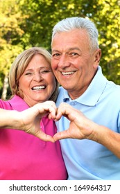 Senior Healthy Couple Showing Heart And Smiling Outdoor. Valentine`s Day Concept