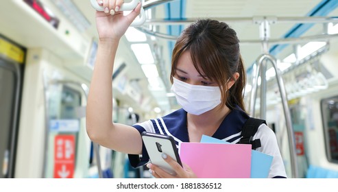 Senior High School Student Girl Use Mobilephone When Commute On Mrt And Wear Face Mask