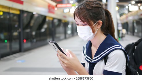 Senior High School Student Girl Use Mobilephone When Wait For Mrt And Wear Face Mask In The Station