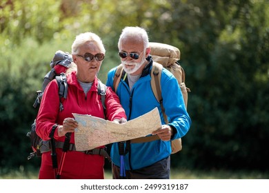 Senior hikers couple looking at the map during the hike in beautiful forest. - Powered by Shutterstock