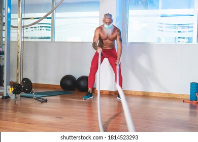 Senior Hipster Working Out With Battle Ropes At The Gym - Focus On Face