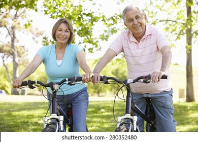 Senior Hispanic Couple Cycling In Park